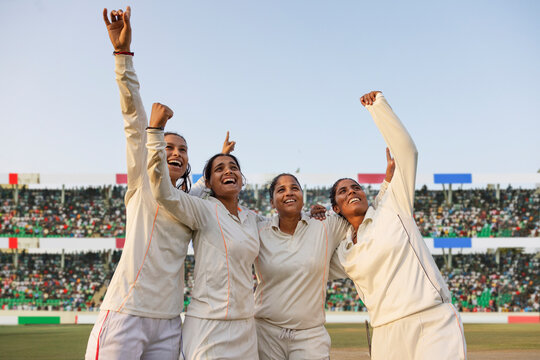 Female cricket team cheering after a successful match