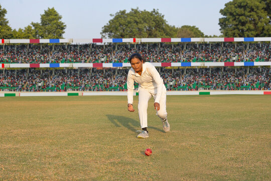 Female cricketer retrieving a ball during a game