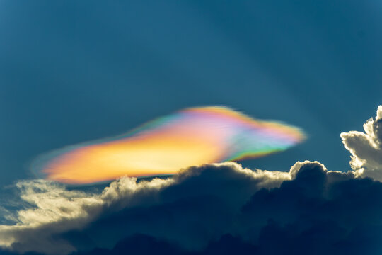 Iridescent cloud colorful sky dramatic cloudscape sunlight atmospheric phenomenon nature vibrant blue sky weather peaceful mood. Iridescent cloud with vibrant colors appears above dramatic dark