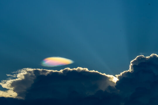 Iridescent cloud sunlight blue sky dramatic nature weather atmospheric phenomenon cloudscape peaceful. Iridescent cloud with sunlight shining through dramatic clouds blue sky creating peaceful