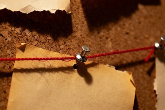 Corkboard with Torn Paper and Red String