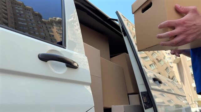 Delivery driver approaches white van and opens the door to retrieve packages for distribution. Efficient delivery and logistics concept are highlighted in this urban setting