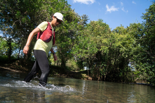 Active woman crossing a river in the forest