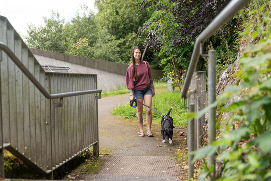 Woman walking dog on leash on park trail with stairs