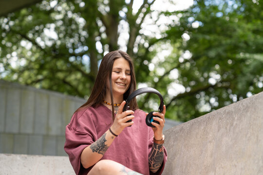 Young woman smiling holding headphones outdoors for leisure