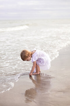 Toddler girl at beach shoreline at sunrise