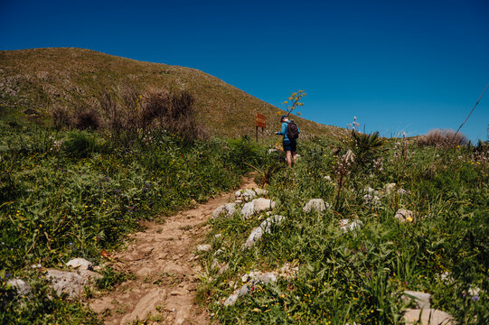 Hiker with a backpack on a sunny mountain trail