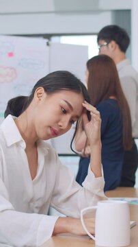 Vertical Screen : young Chinese businesswoman working stress out with project research problem on computer desktop in meeting room at small modern office. Asia people occupational burnout syndrome.