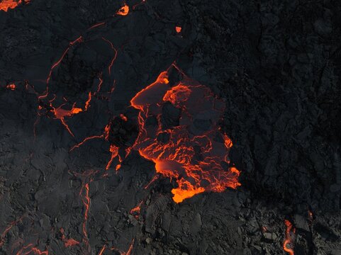 Aerial view of the glowing orange lava flow from the Litli-Hrutur volcanic eruption moving through dark, jagged basaltic rock in Grindavik, Grindavikurbaer, Iceland.