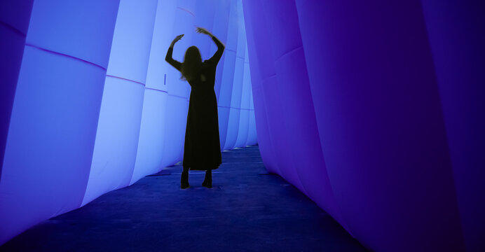 abstract art with silhouette of a woman dancing in a black dress in purple blue tunnel