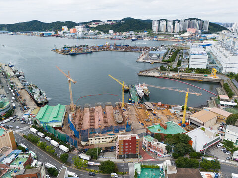 Drone footage of a shipyard and dry dock construction site in Busan South Korea featuring docked vessels tower cranes shipbuilding facilities coastal industrial infrastructure