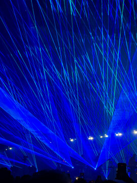 blue laser light beams and silhouette of crowd at music concert
