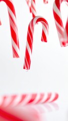 Fototapeta premium Festive Red and White Candy Canes Hanging Against a Bright White Background for Holiday Celebrations