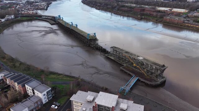 Aerial perspective circling around Dunston Staiths in Gateshead, the iconic timber structure which was used to load coal onto ships. The Staiths shows signs of deterioration and a gap caused by arson