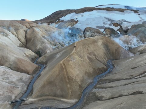 Aerial view of Kerlingarfjoll geothermal area with steaming vents, snow-capped mountains, and a hiking trail winding through the landscape in Hveragerdi, Hveragerdisbaer, Iceland.