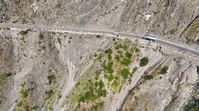 Aerial tracking of cargo trucks and oil tanker on steep Dangerous Himalayan cliff road.