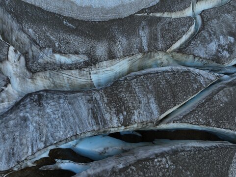 Aerial view of the rugged glacial landscape of Kerlingarfjoll with deep crevasses, textured ice formations, and dark volcanic ash deposits in Hveragerdi, Hveragerdisbaer, Iceland.