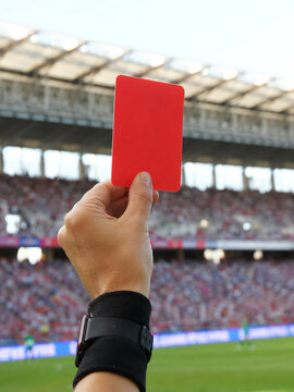 Close-up photo of a soccer referee's hand holding a red card.
