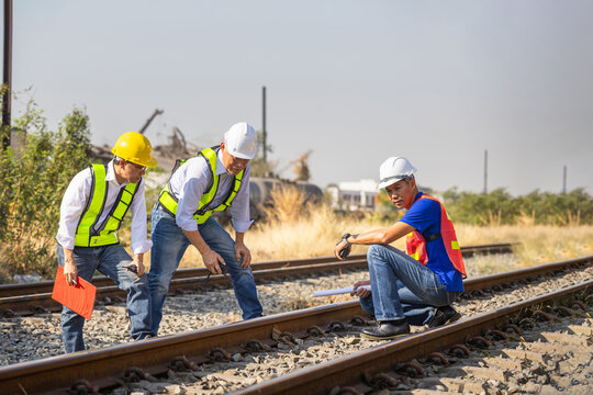 Engineers inspecting railway tracks at a freight terminal, Industrial team of engineers examining railway infrastructure, Railway logistics engineers conducting a site inspection at a cargo station