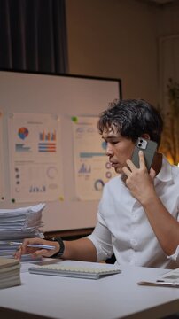 Stressed businessman talking on phone working overtime at night office