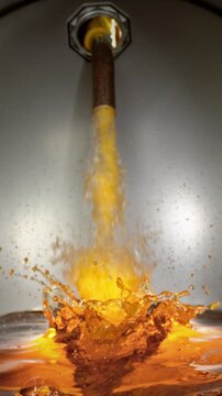 Super slow motion (1000 fps) gasoline pouring into metal fuel tank, dynamic splash and turbulence. Concept of refueling, energy supply and fuel storage, dramatic lighting, industrial environment.