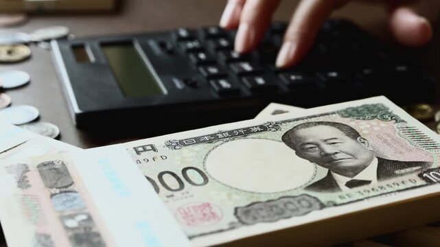 黒い計算機でお金を計算する　札束　貯金　資産運用　投資