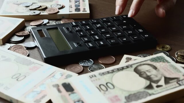 黒い計算機でお金を計算する　札束　貯金　資産運用　投資