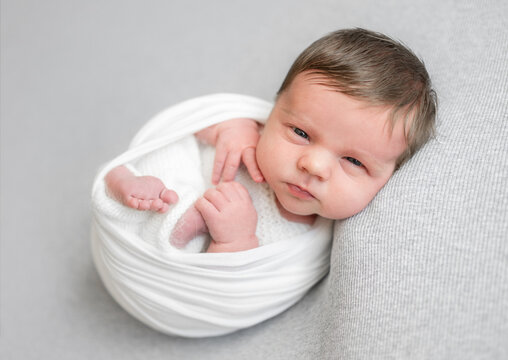 Newborn Baby Wrapped In Blanket At A Newborn Photographer Photoshoot