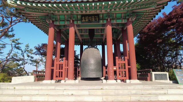 Slow push in shot of ancient style Korean pavilion and bronze bell
