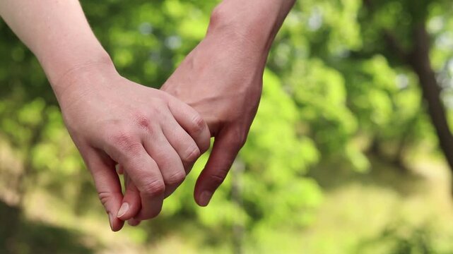 Close-up of two women's hands holding each other. Two women holding hands while walking in a park. A symbol of trust, tenderness and LGBT relationships. Concept of love, friendship and equality