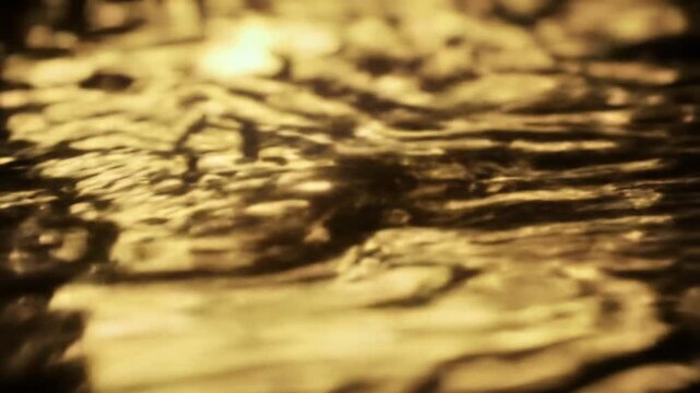 Extreme close-up of a mesmerizing, continuously flowing, shimmering golden liquid surface with metallic luster and dynamic reflections, macro video with razor-sharp focus and ethereal bokeh in a