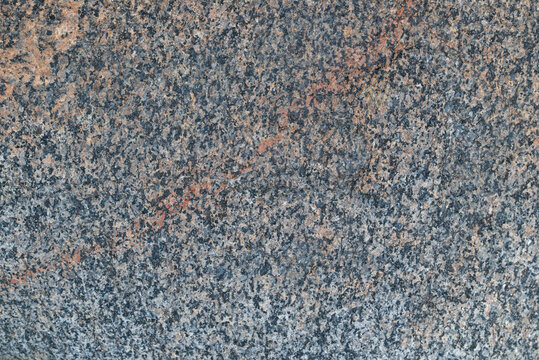 Stone texture. Dark granite stone texture with a contrasting orange quartz vein close up.