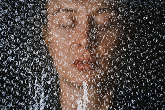 Face trapped behind transparent bubble wrap depicting depression