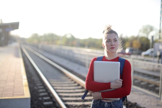 Young woman with laptop waits at train station