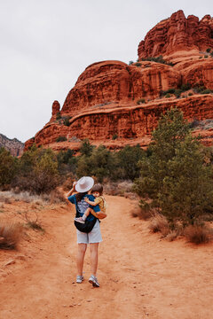Mother carrying toddler on trail in Sedona Arizona