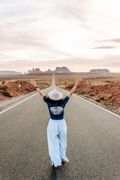 Woman walking on iconic road in Monument Valley from Back