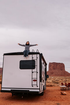Woman sitting on RV roof in Monument Valley desert
