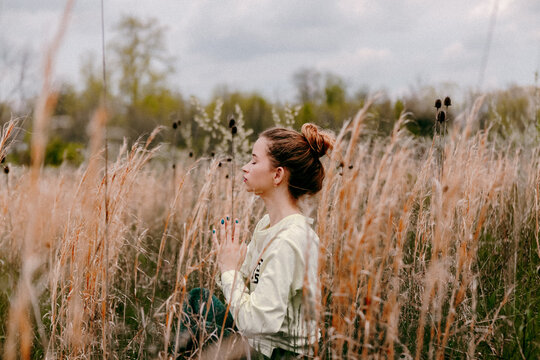 Girl in tall grass meditating horizontal