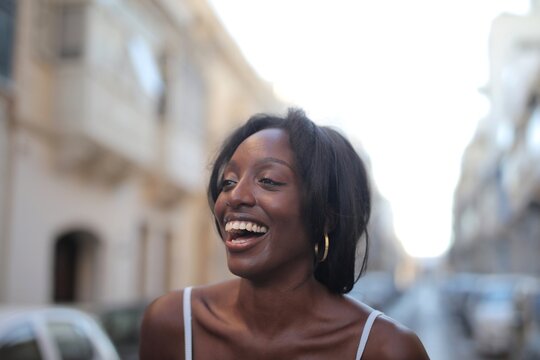 Young Black woman laughing happily on a city street