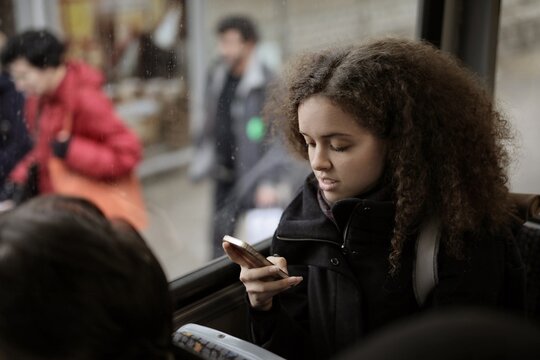 Woman with curly hair looks at her phone on the bus
