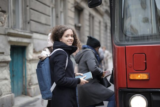 Cheerful young woman boards a city bus