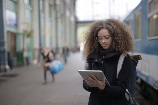 Young woman with glasses using tablet at train station
