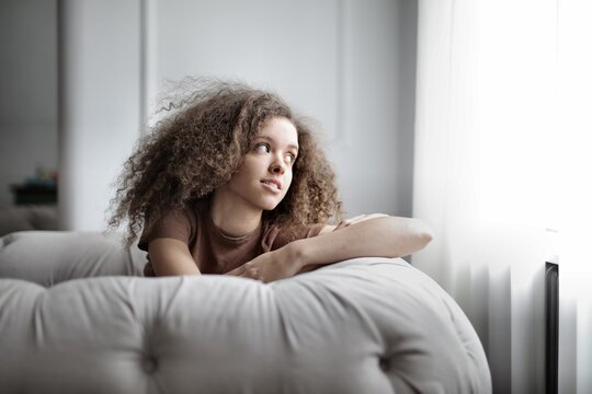 Thoughtful girl with curly hair relaxes at home