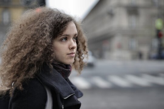 Young woman with curly hair waiting on a city street