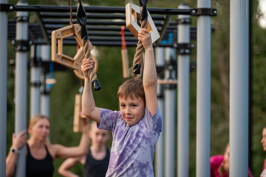 Determined boy hangs from ropes on obstacle course