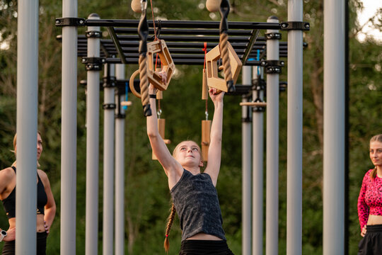 Young girl hanging from an outdoor obstacle course