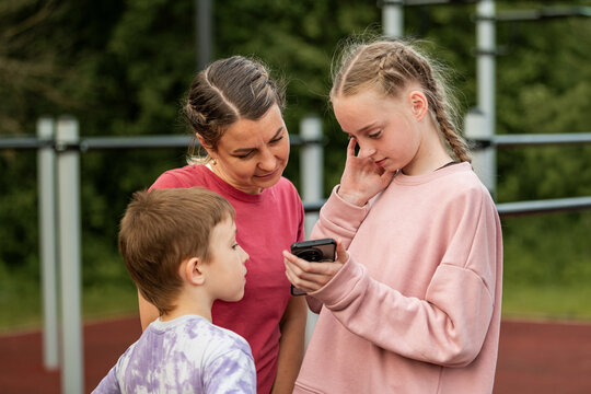 Mother with daughter and son share a phone
