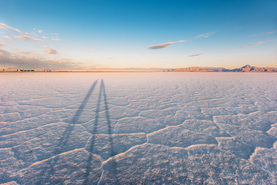 Long human shadows on a cracked desert salt flat