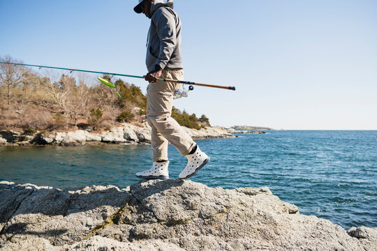 Man walking on rocky coastline with fishing gear