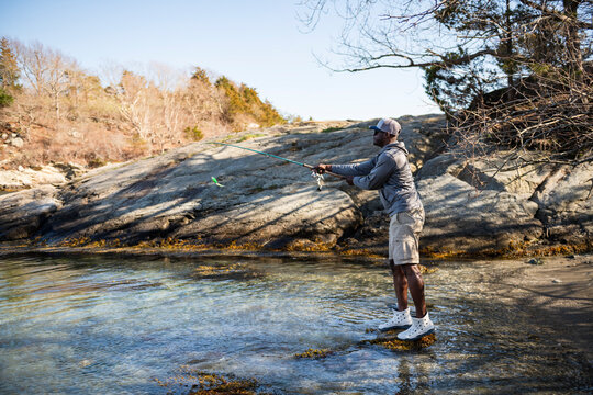Black man fishing in shallow coastal water on a sunny day